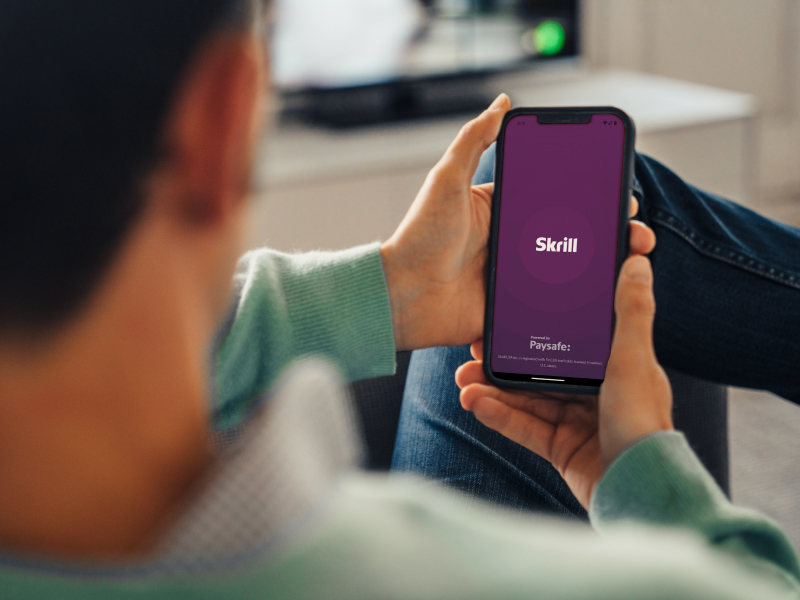 man looking at his mobile phone with Skrill app open
